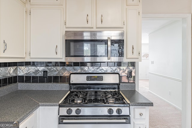 kitchen featuring backsplash, stainless steel appliances, carpet floors, ornamental molding, and white cabinets