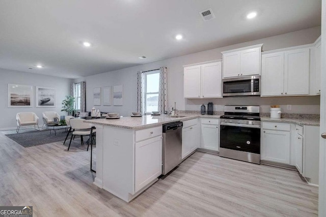 kitchen featuring stainless steel appliances, sink, light wood-type flooring, and white cabinets