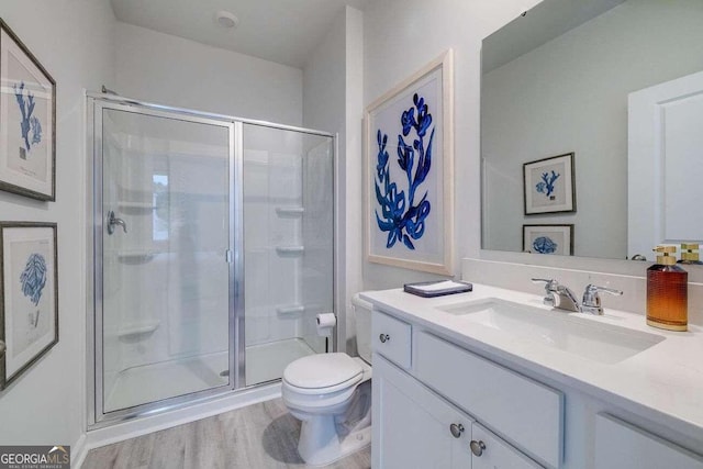 bathroom with vanity, hardwood / wood-style floors, a shower with shower door, and toilet