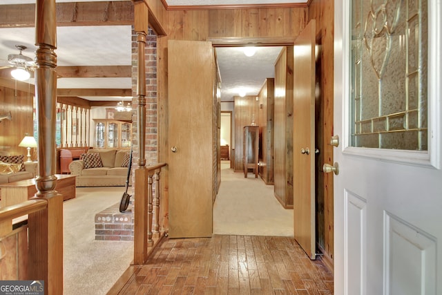 corridor with wood walls, hardwood / wood-style floors, and beam ceiling