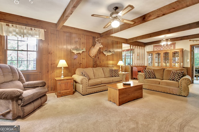 carpeted living room featuring ceiling fan with notable chandelier, wood walls, and beamed ceiling