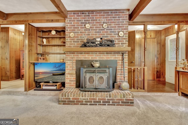 living room with beamed ceiling, wooden walls, light carpet, and a wood stove