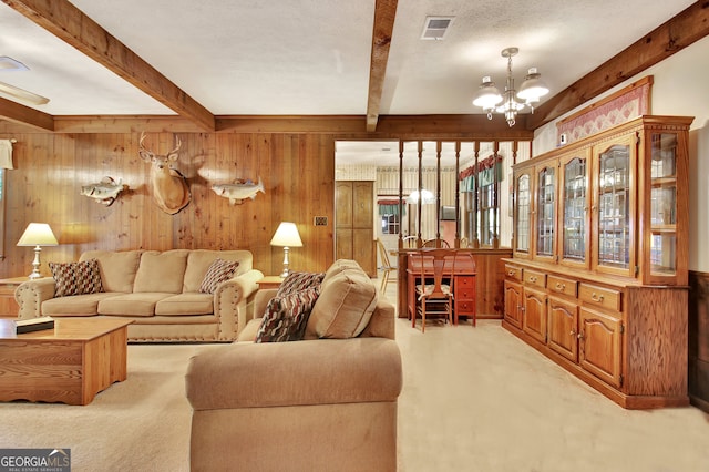 living room featuring beam ceiling, light carpet, a textured ceiling, and wooden walls