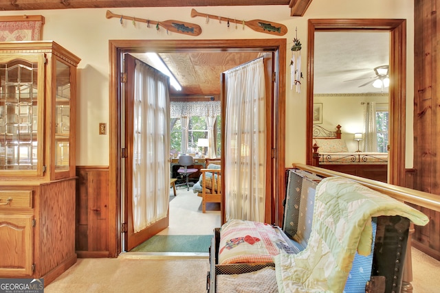 hall with wood walls and light carpet