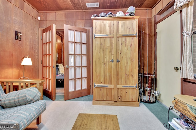 living area featuring wood ceiling, wooden walls, and light colored carpet