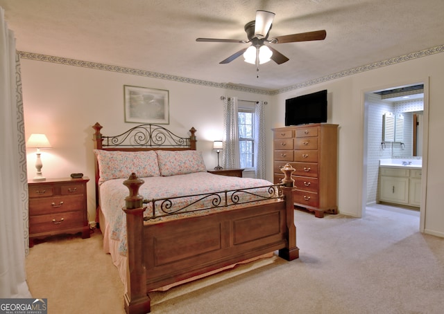 bedroom featuring a textured ceiling, light carpet, ceiling fan, and ensuite bathroom