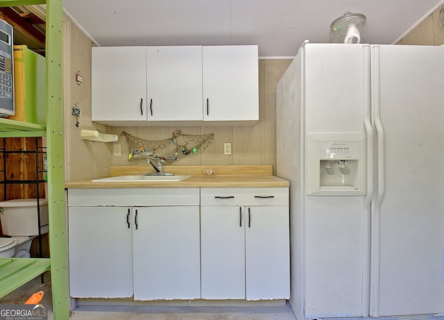 kitchen with white cabinets, sink, and white refrigerator with ice dispenser