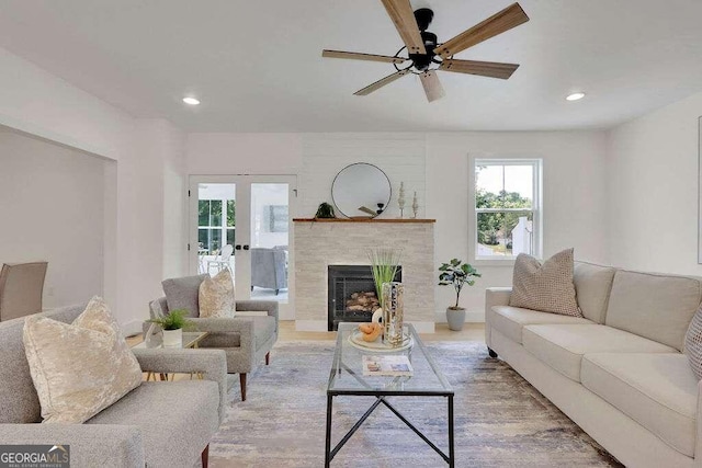 living room featuring french doors, wood-type flooring, ceiling fan, and a tile fireplace