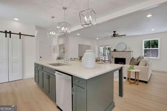 kitchen with dishwasher, a barn door, sink, a kitchen island with sink, and pendant lighting