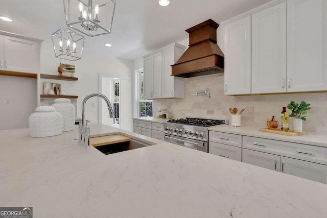 kitchen with white cabinetry, custom range hood, pendant lighting, sink, and stainless steel range