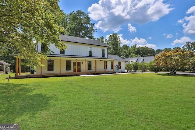 rear view of house with a lawn and a porch