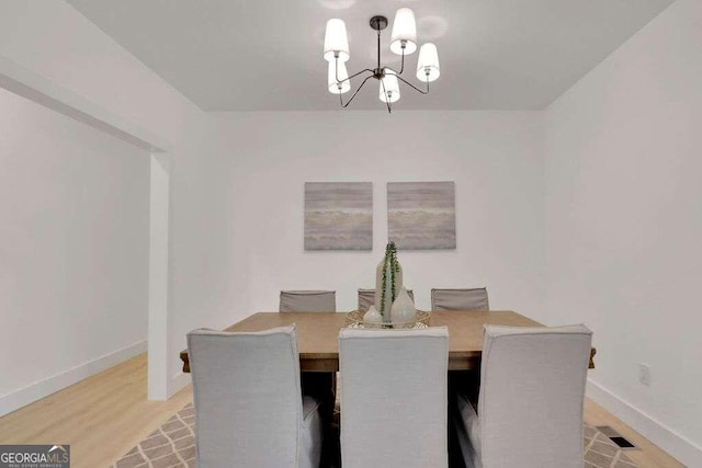 dining room featuring light wood-type flooring and a notable chandelier