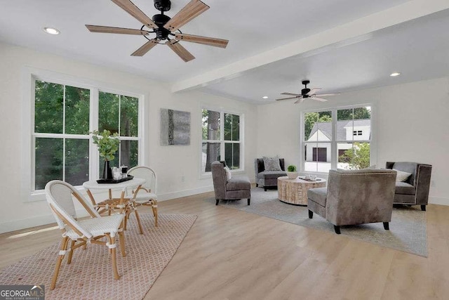 living room featuring light wood-type flooring, ceiling fan, and beamed ceiling