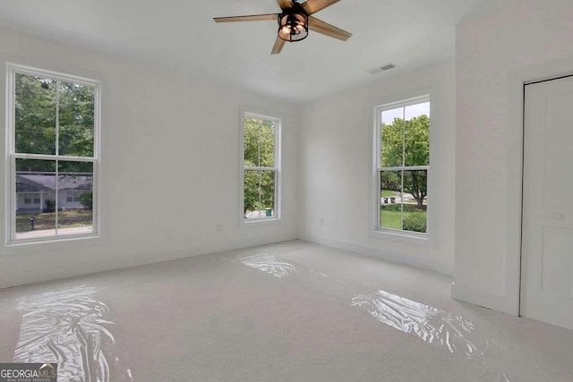 spare room with light carpet, a healthy amount of sunlight, and ceiling fan