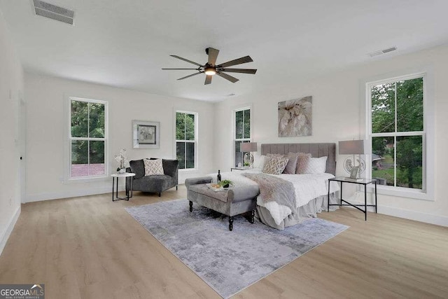 bedroom featuring ceiling fan, multiple windows, and light wood-type flooring