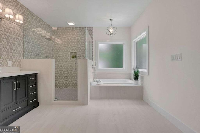 bathroom with vanity, an inviting chandelier, and separate shower and tub