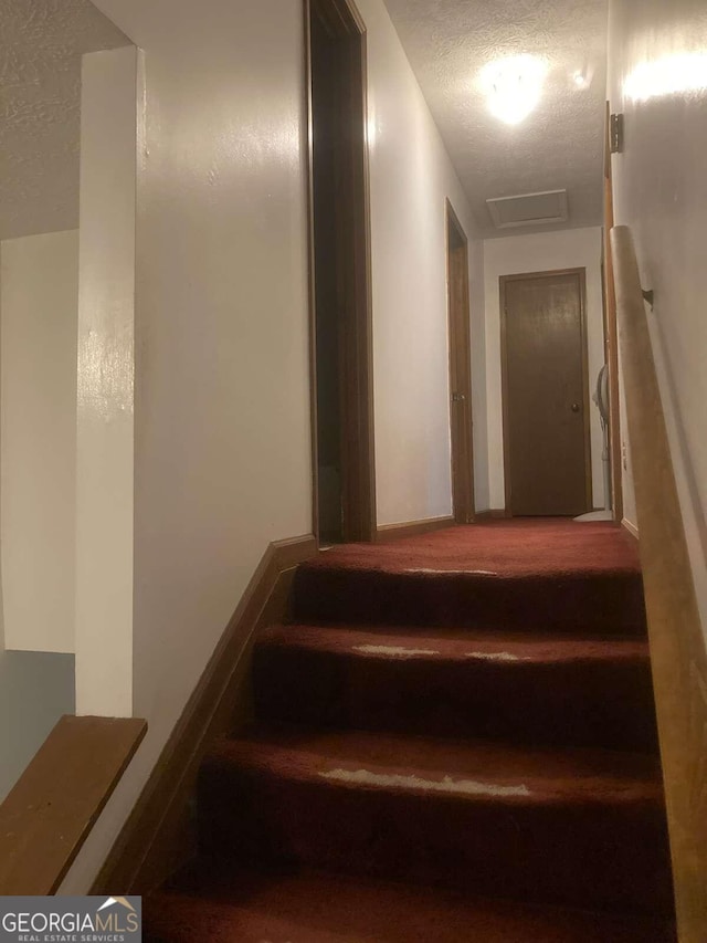 staircase featuring a textured ceiling