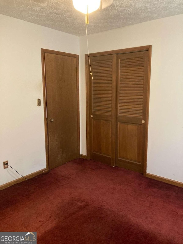 unfurnished bedroom with carpet floors, a textured ceiling, and a closet