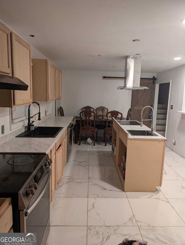 kitchen with light brown cabinets, sink, a barn door, range hood, and stainless steel appliances