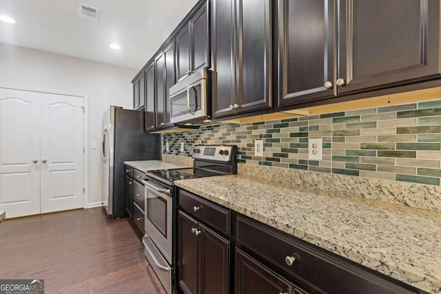 kitchen with dark brown cabinetry, appliances with stainless steel finishes, light stone countertops, dark wood-type flooring, and decorative backsplash