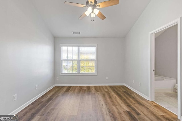 spare room featuring dark wood-type flooring, vaulted ceiling, and ceiling fan