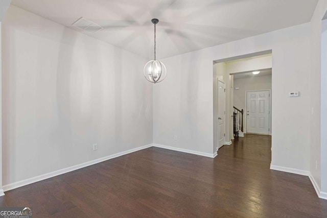 spare room with dark hardwood / wood-style flooring and a chandelier