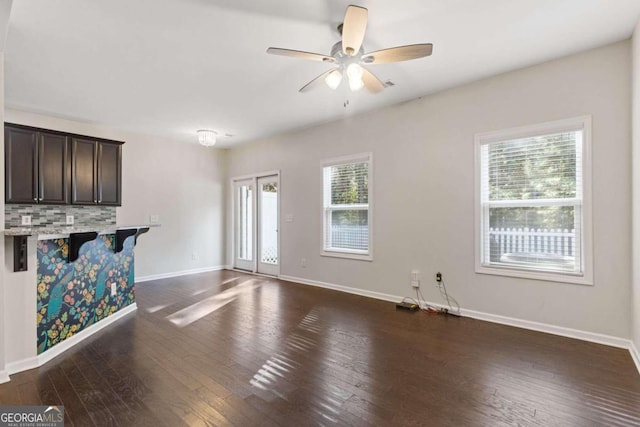 unfurnished living room featuring a healthy amount of sunlight, dark hardwood / wood-style floors, and ceiling fan