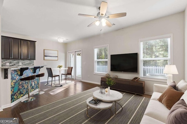 living room featuring a wealth of natural light, dark wood-type flooring, and ceiling fan