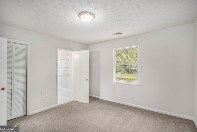 unfurnished bedroom featuring a closet, carpet, and a textured ceiling