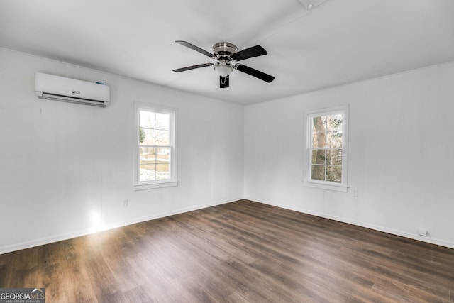 spare room featuring dark wood-type flooring, a wealth of natural light, an AC wall unit, and ceiling fan