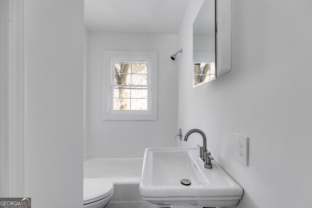 bathroom featuring toilet, a shower, and sink