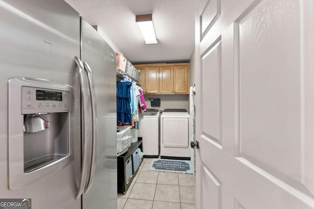 washroom with light tile patterned floors, cabinets, and washer and dryer