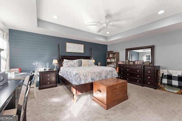 carpeted bedroom featuring ceiling fan, wooden walls, and a raised ceiling