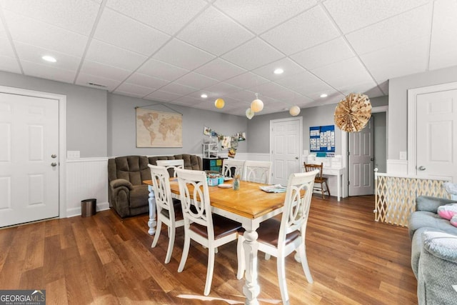 dining space featuring a drop ceiling and hardwood / wood-style flooring