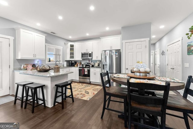 kitchen with dark wood-type flooring, white cabinets, and stainless steel appliances