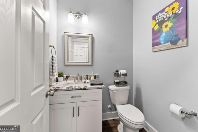 bathroom with wood-type flooring, vanity, and toilet