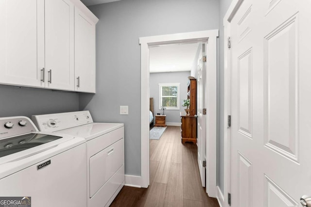 laundry area with dark hardwood / wood-style flooring, cabinets, and washer and clothes dryer