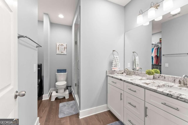 bathroom featuring hardwood / wood-style flooring, a shower with shower door, vanity, and toilet