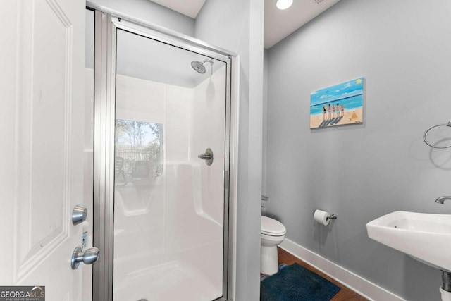 bathroom featuring walk in shower, wood-type flooring, sink, and toilet