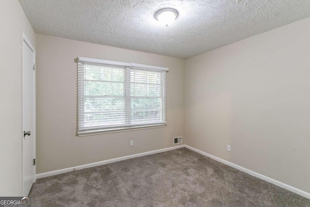 spare room with a textured ceiling and carpet flooring