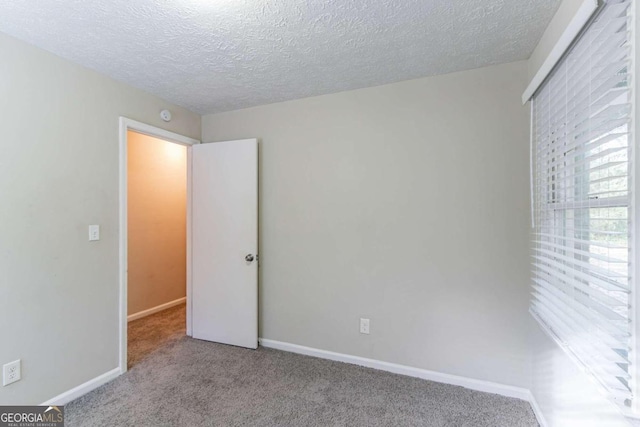 spare room with a textured ceiling and light colored carpet