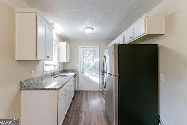 kitchen with appliances with stainless steel finishes, dark hardwood / wood-style flooring, light stone countertops, sink, and white cabinets