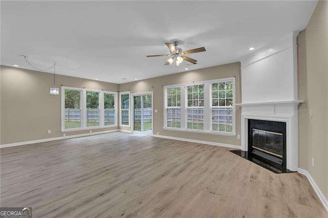 unfurnished living room with light hardwood / wood-style floors, ceiling fan, and a healthy amount of sunlight