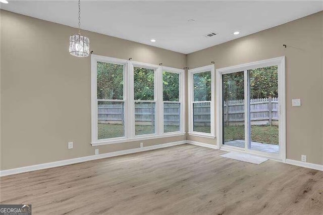 unfurnished dining area featuring light wood-type flooring and an inviting chandelier