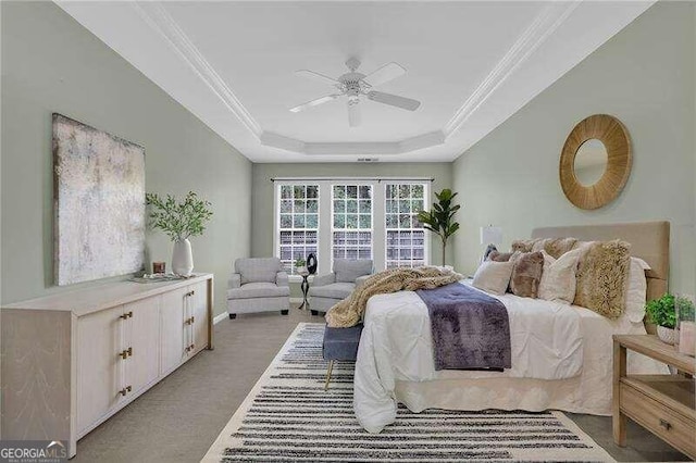 carpeted bedroom featuring ornamental molding, ceiling fan, and a tray ceiling