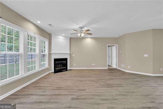 unfurnished living room with light wood-type flooring, ceiling fan, and a large fireplace