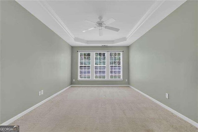 carpeted spare room featuring ornamental molding, ceiling fan, and a raised ceiling