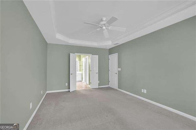 carpeted spare room featuring ornamental molding, ceiling fan, and a tray ceiling