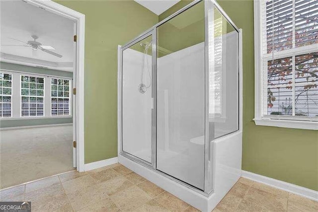 bathroom featuring ceiling fan, a shower with door, and a healthy amount of sunlight