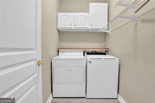 laundry area with cabinets, light wood-type flooring, and washer and clothes dryer